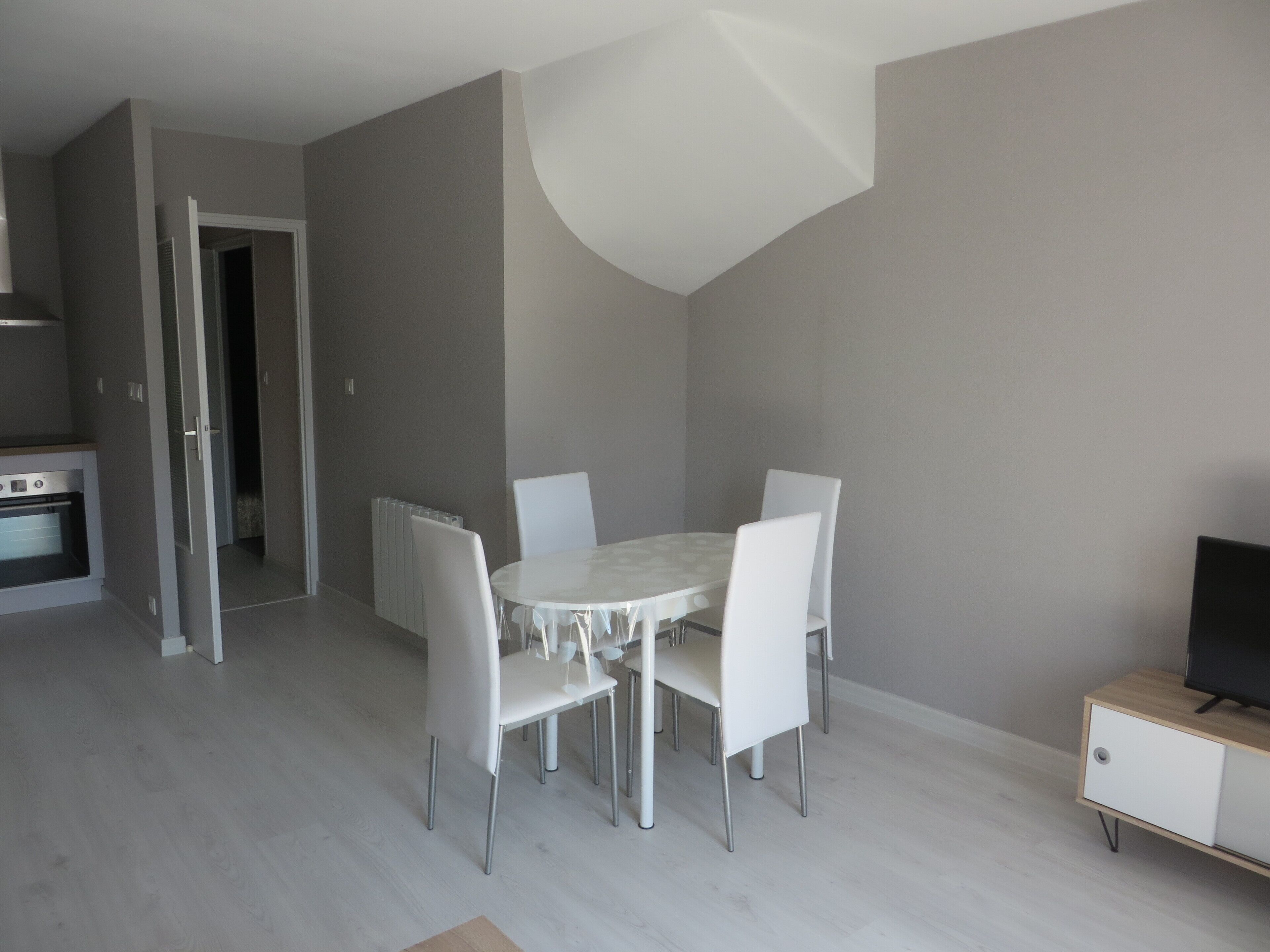 A modern kitchen with a built-in oven and a dining area with a round table and four chairs.