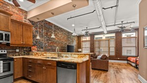 A kitchen with wooden cabinets, a granite countertop, and a dishwasher. - The Johnny Cash Dual Condos Downtown at Printer's Alley & Steps to Broadway (Nashville)