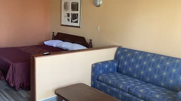 A room with a bed, a sofa, a small table, and a chair.