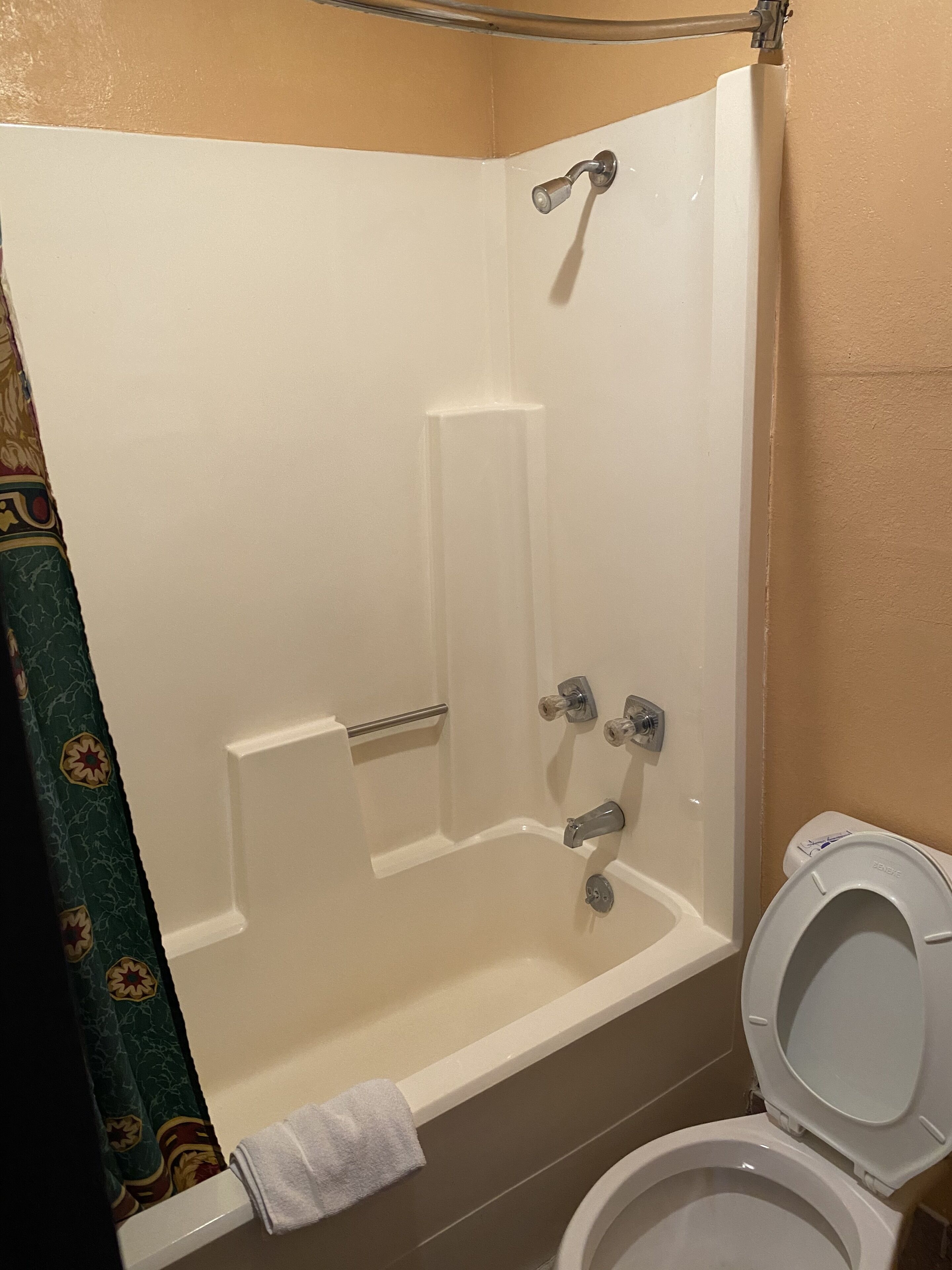 A bathroom with a bathtub, toilet, and shower curtain.