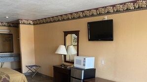 A hotel room with a bed, a desk, a microwave, a refrigerator, a TV, and a mirror. - Executive Inn and Suites (Mission)