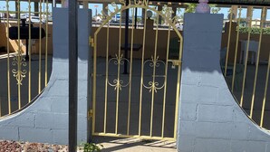 A gated entrance with a metal gate and decorative elements, leading to a covered area with a corrugated roof. - Executive Inn and Suites (Mission)