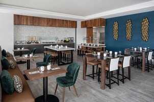 Un restaurante moderno con varias mesas y cabinas, un revestimiento de pared de ladrillo y decoración mural.