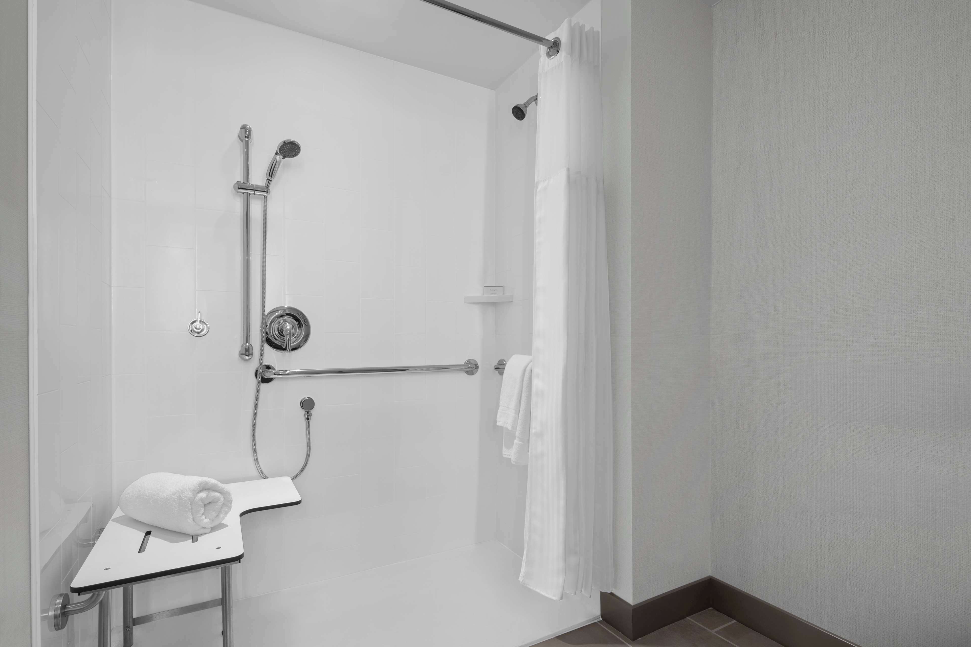 Een moderne badkamer met een inloopdouche, handgrepen en een handdoekrek.