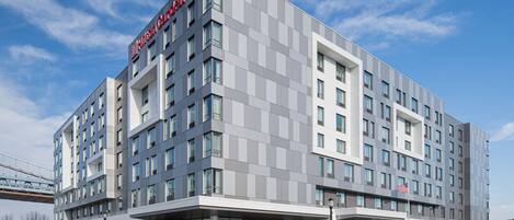 A modern hotel with a flat roof, large windows, and a prominent American flag.
