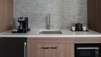 Una cocina moderna con un lavamanos de acero inoxidable, una cafetera, un microondas y armarios de madera.