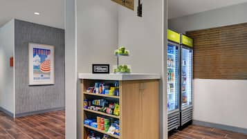 Un vestíbulo de hotel con un mini bar, un refrigerador y un cartel que indica 'Home2MKT'.