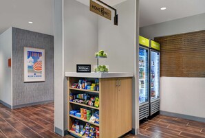 A hotel lobby with a minibar, a refrigerator, and a sign indicating 'Home2MKT'.
