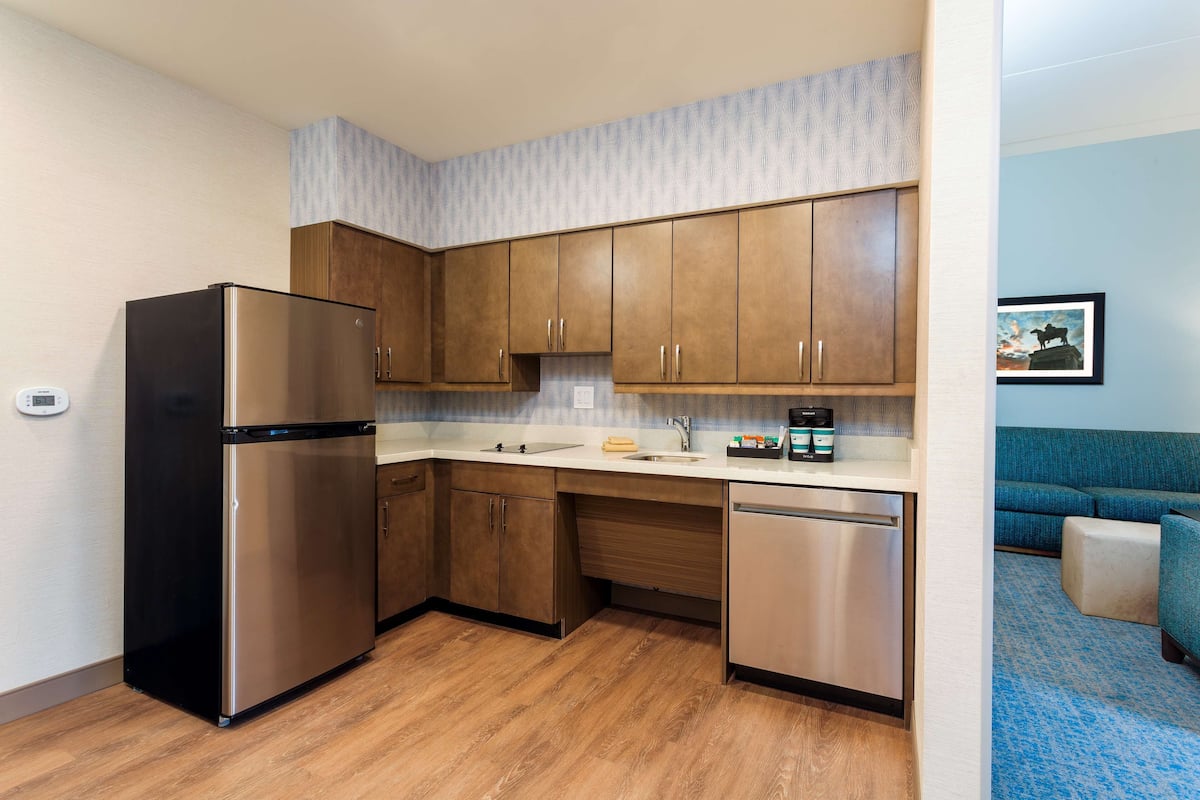 A compact kitchen with wooden cabinets, a stainless steel refrigerator, and a dishwasher.