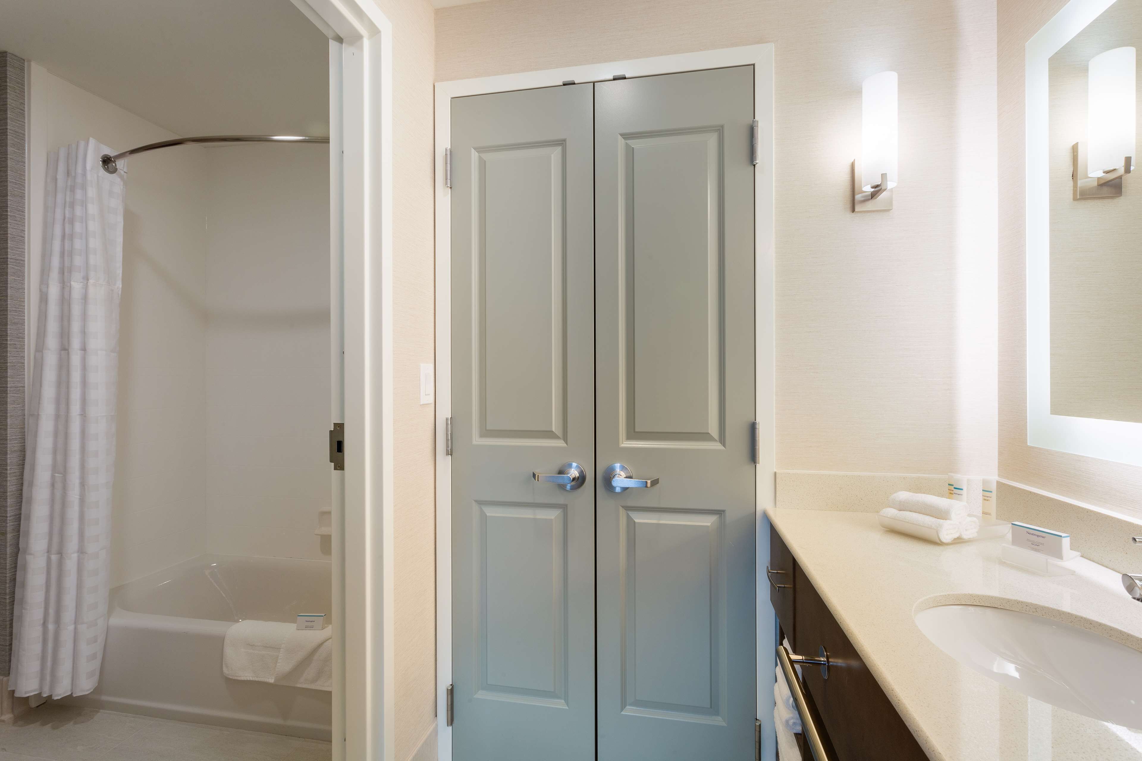 A bathroom with a shower, a double door, a sink, and a mirror.