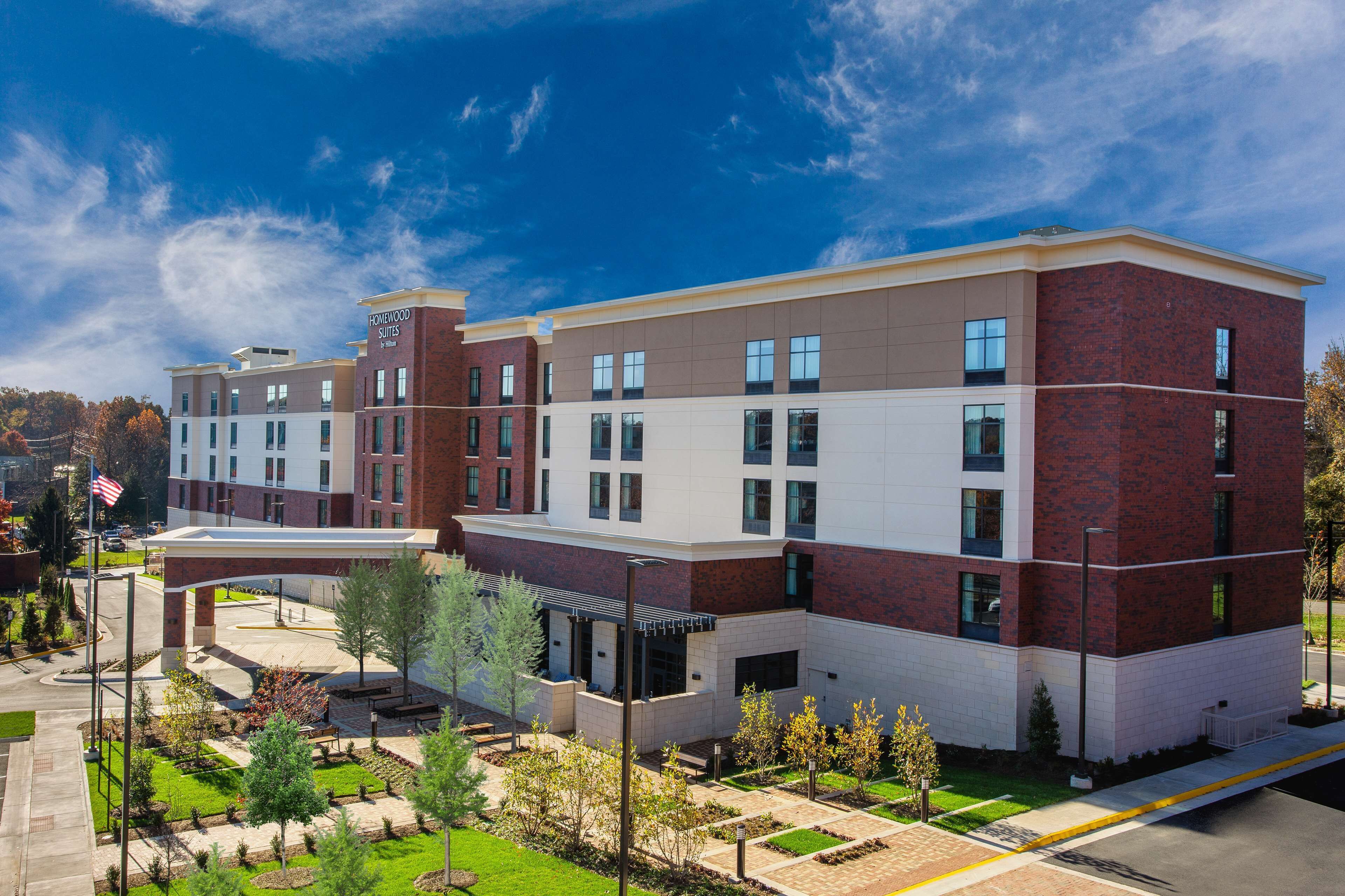 A modern hotel with a brick facade, multiple windows, and a landscaped courtyard.