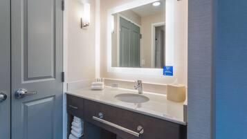 Une salle de bain moderne avec un grand miroir, un lavabo et un porte-serviettes.