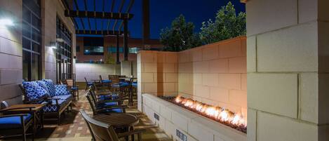 Ein Patio im Freien mit Sitzgelegenheiten und einem integrierten Feuerbereich.