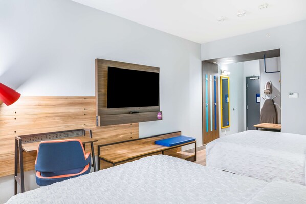 A hotel room with a bed, a desk, a chair, a TV mounted on the wall, and a bathroom visible through an open door. - Tru By Hilton Midland (Midland)