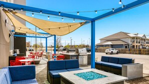 Un área de patio al aire libre con asientos azules, una parrilla y mesa de billar.