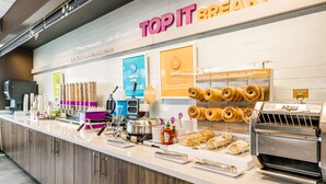 Una barra de desayuno con barcos de gofre, huevos, bagels, donas y muffins.