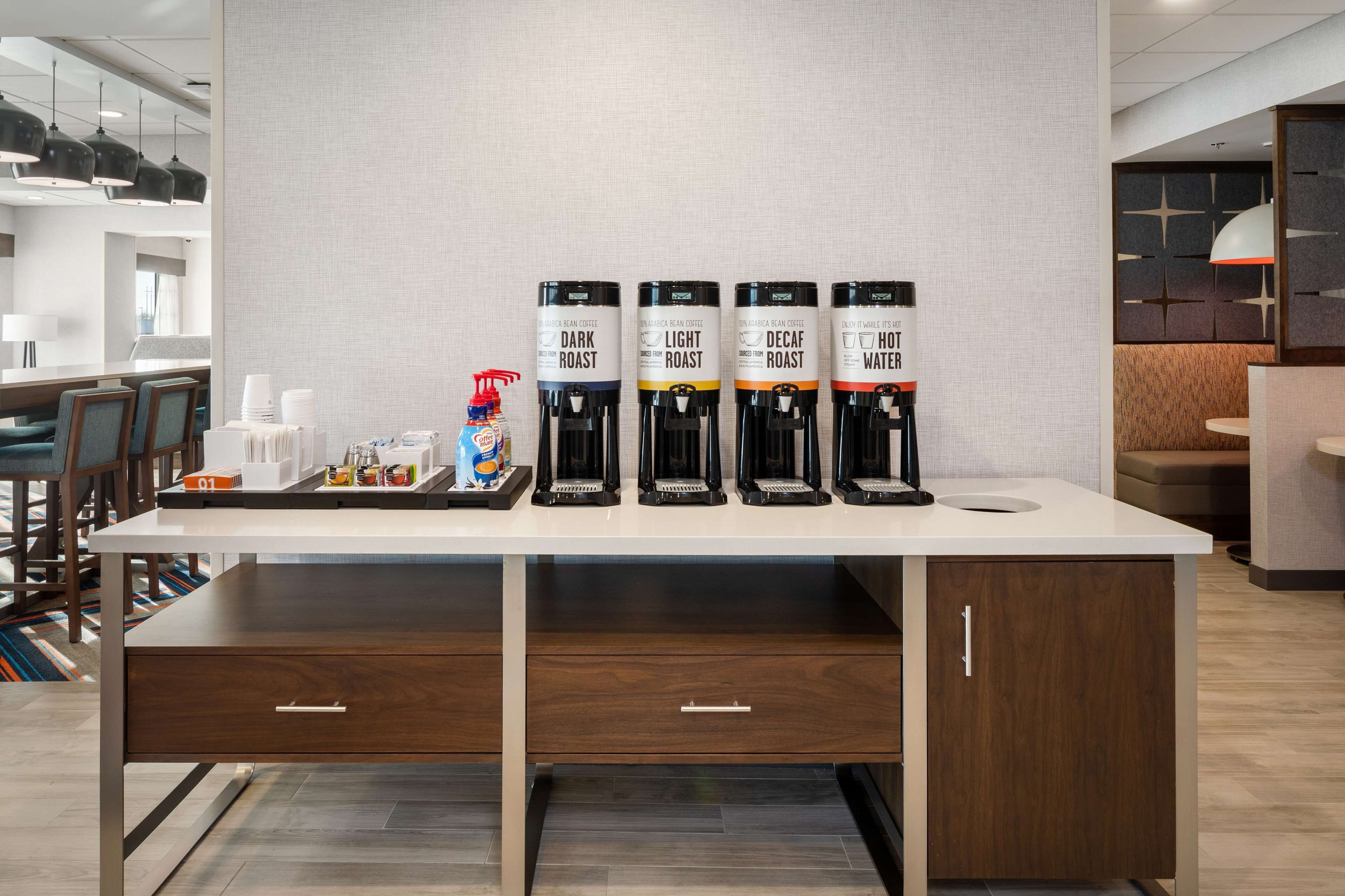 Una estación de café con cuatro dispensadores de café: tueste oscuro, tueste claro, descafeinado y agua caliente.