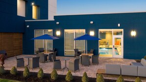 An outdoor patio area with seating and umbrellas, a pool, and a building entrance. - Hampton Inn Circleville (Circleville)