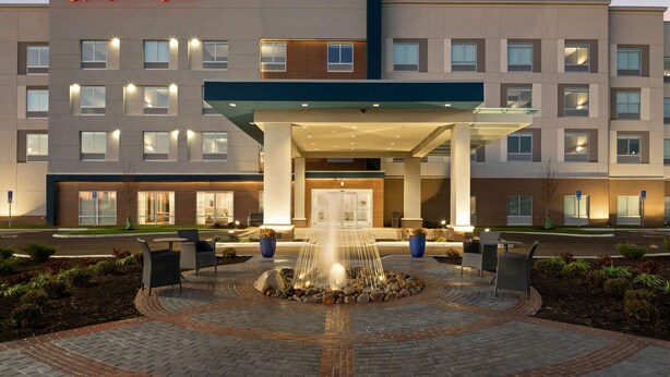 A Hampton Inn hotel with a central fountain, outdoor seating, and a well-lit entrance. - Hampton Inn Circleville (Circleville)