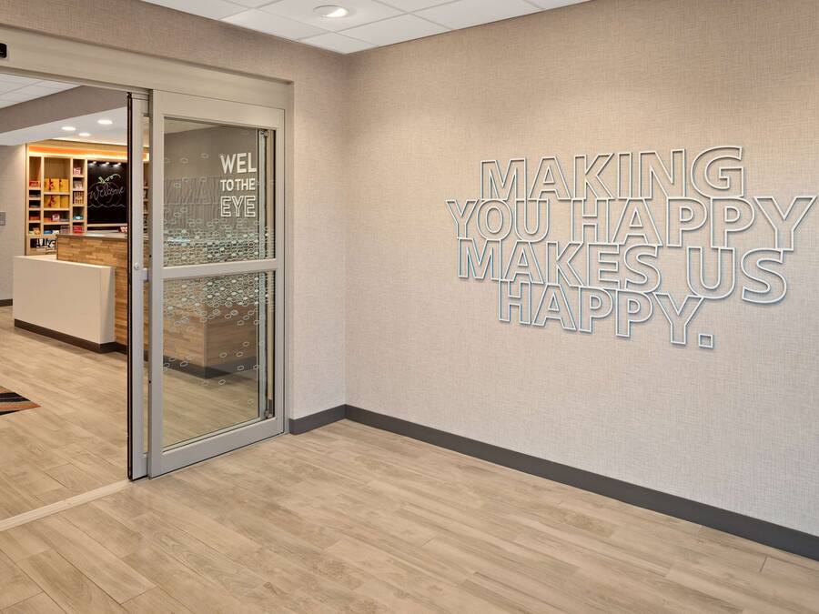 A reception area with a glass door, a wall with motivational text, and a wooden floor.