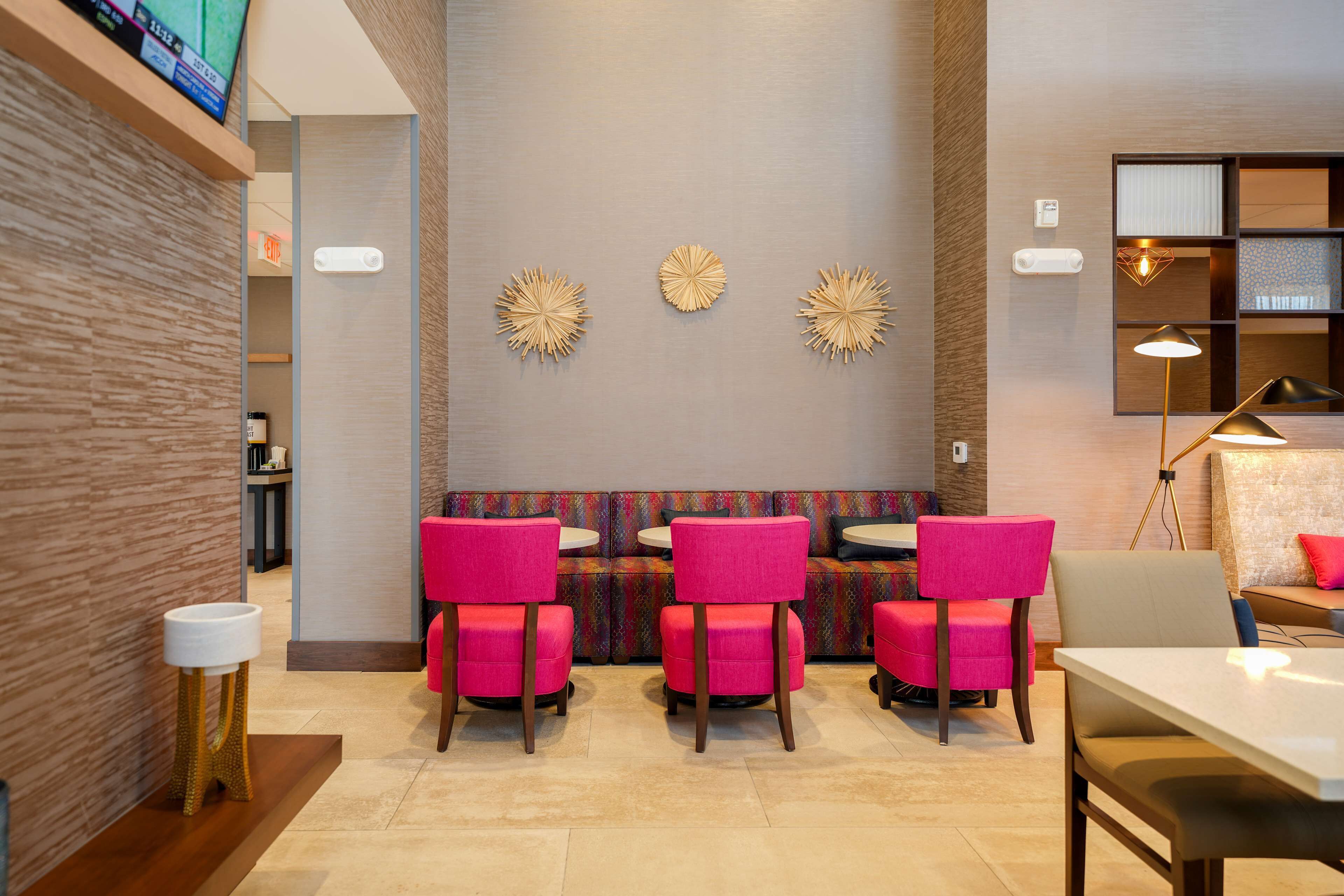 Un interior moderno con una zona de estar que incluye sillas rosadas, una mesa blanca y decoración mural.