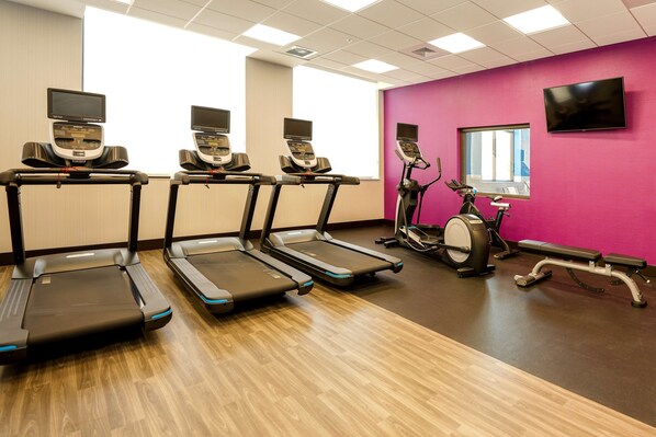 Un gimnasio con cintas de correr, elípticas y bicicletas estáticas.
