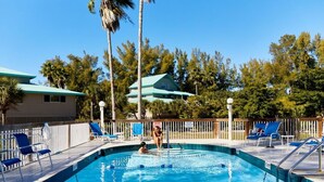 A swimming pool with clear blue water, surrounded by a wooden deck with blue lounge chairs. - Little Gasparilla Island Getaway (Placida)