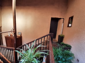 A staircase with wooden railings, a potted plant, and a door leading to another room.