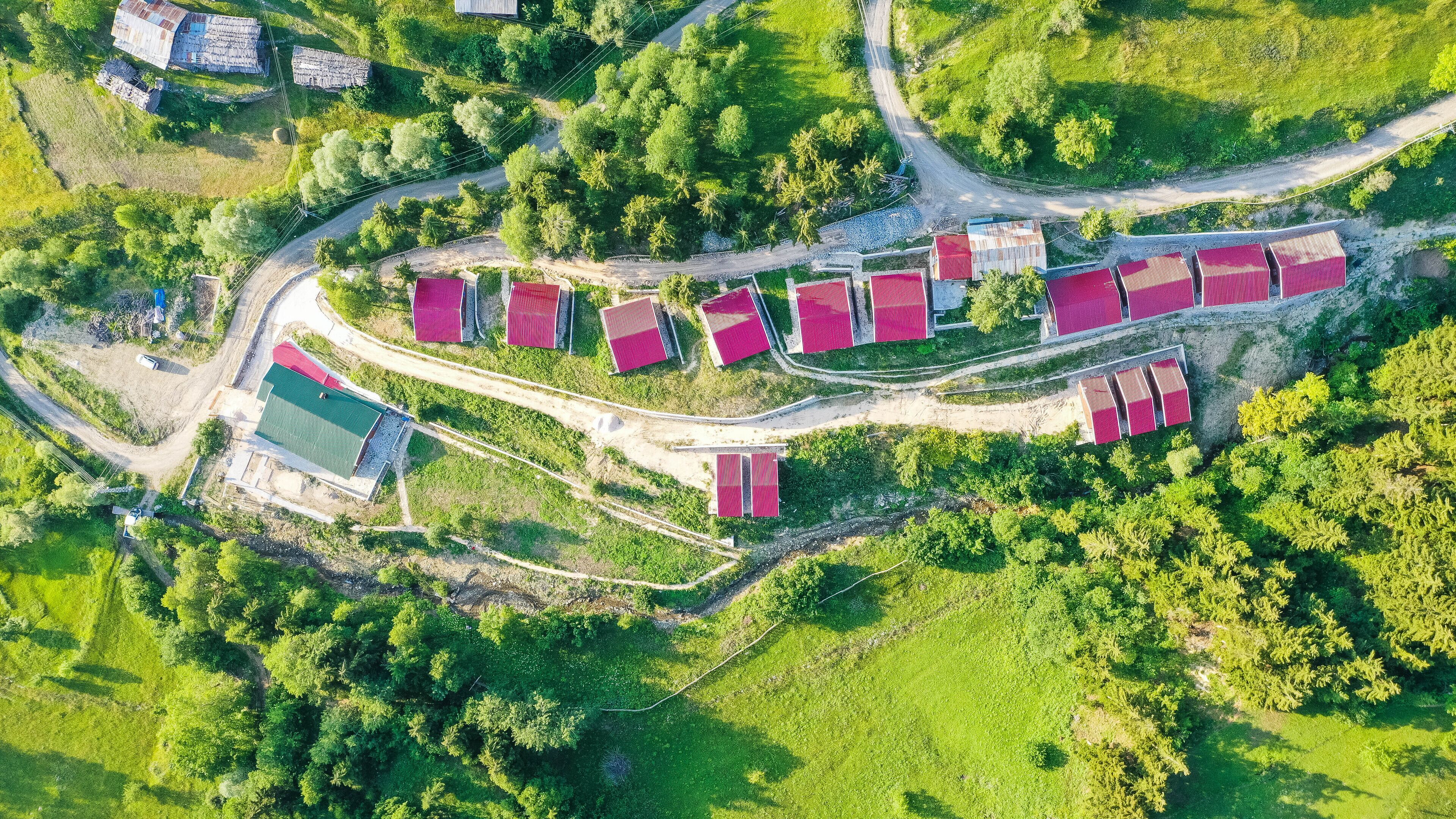 An aerial view of a rural property with multiple red-roofed buildings, winding roads, and surrounding greenery.