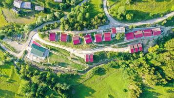An aerial view of a rural property with multiple red-roofed buildings, winding roads, and surrounding greenery.