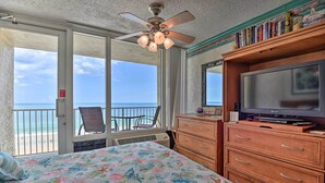 Un dormitorio con cama, televisión, estantería y vista al océano.
