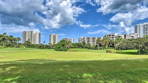 Un área verde y cuidada, con cielo despejado y altos edificios al fondo.