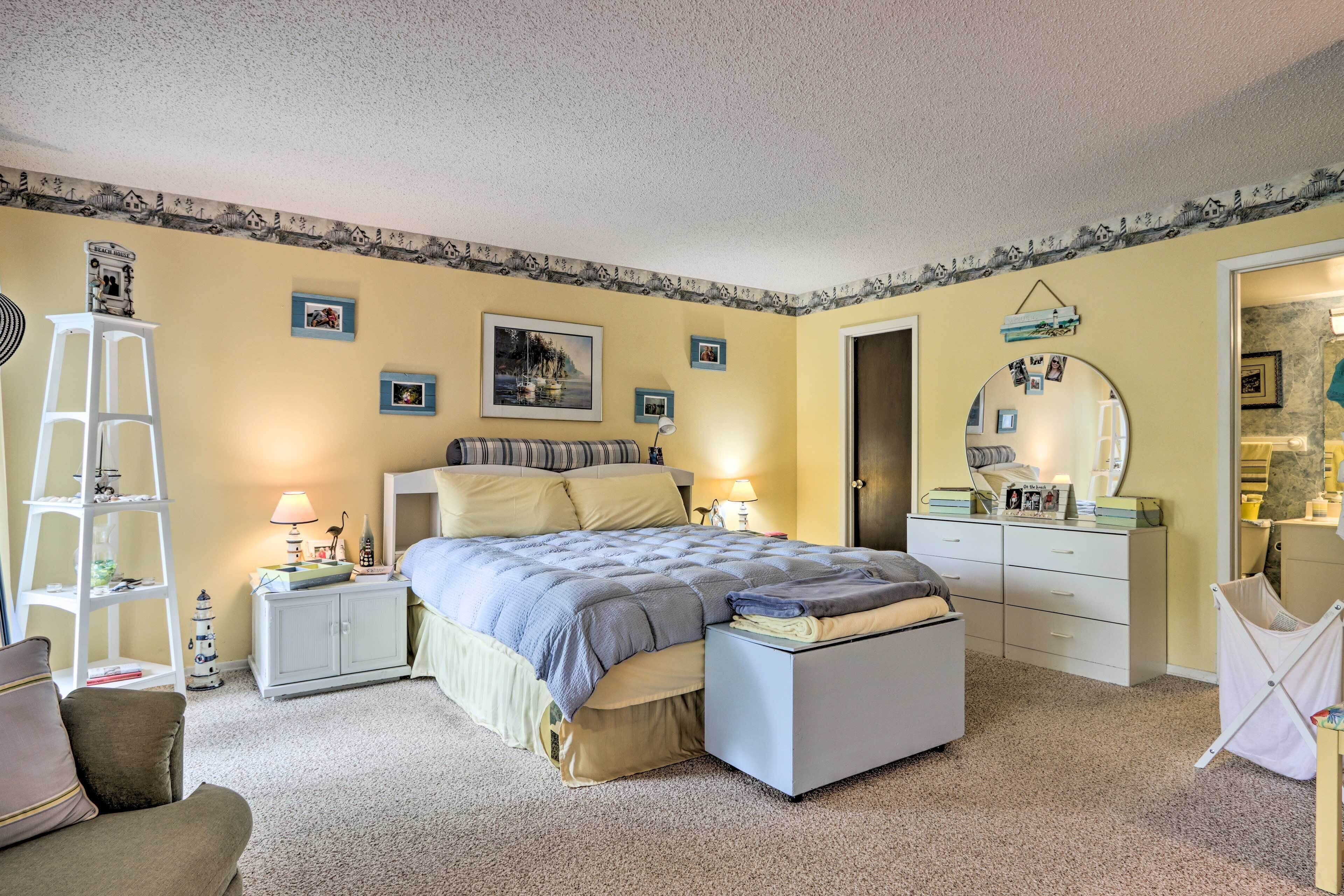 Une chambre à coucher comprenant un lit, des tables de chevet, une commode, une chaise et une armoire.
