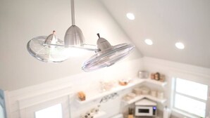 Une cuisine moderne avec un plafond blanc, des luminaires suspendus et un micro-ondes visible.