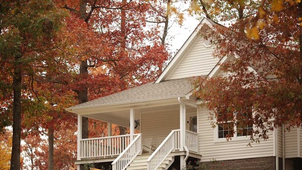 Une maison à deux étages avec un porche et un escalier menant à l’entrée.