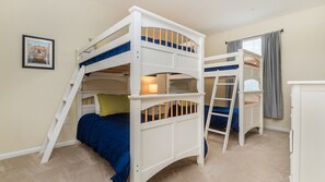 Dormitorio con literas, un escritorio pequeño y una ventana con cortinas.