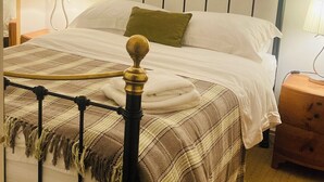 A bed with a headboard, a bedside table, a lamp, and a wall-mounted decoration.