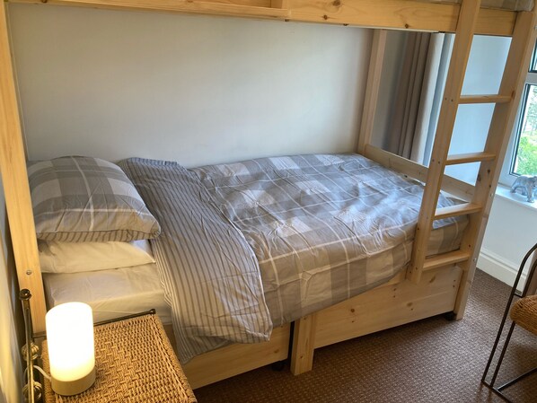 A bunk bed with a wooden frame, a window with curtains, and a small table with a lamp. - Number 2, The Morays. Two bedroom house (Blackford)