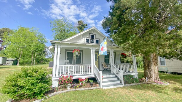 A two-story house with a porch, a flag, and a large tree. - Vintage Cottage in Wanchese (Wanchese)