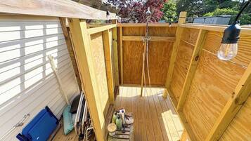 A wooden deck with a blue folding chair, a small table with various items, and a hanging light fixture.