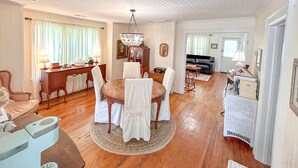 A dining area with a round table, chairs, a chandelier, and a sofa. - Vintage Cottage in Wanchese (Wanchese)