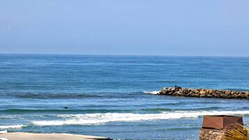 A coastal view with a clear sky, calm sea, and a rocky breakwater.