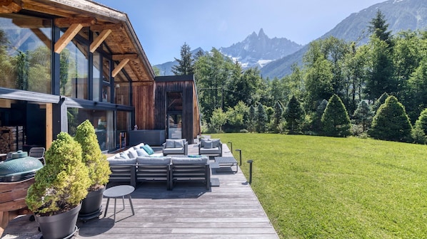 Un bâtiment moderne en bois doté d’une terrasse, d’un espace salon extérieur et offrant une vue sur les montagnes.