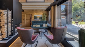 A modern interior with a sofa, two chairs, a fireplace, and a large window.