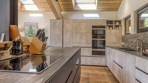 A modern kitchen with a central island, built-in appliances, and a skylight. - Chalet Maple Leaf: Superb luxury chalet near the golf course (Chamonix)