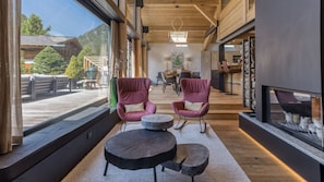 A modern interior with two rocking chairs, a round table, and a fireplace.