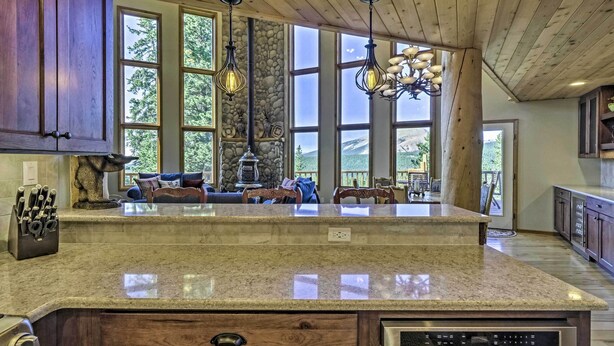 A kitchen with a large island, wooden cabinets, and a stone accent wall. - Spacious Fairplay Retreat w/ Hot Tub & Fire Pit! (Fairplay)