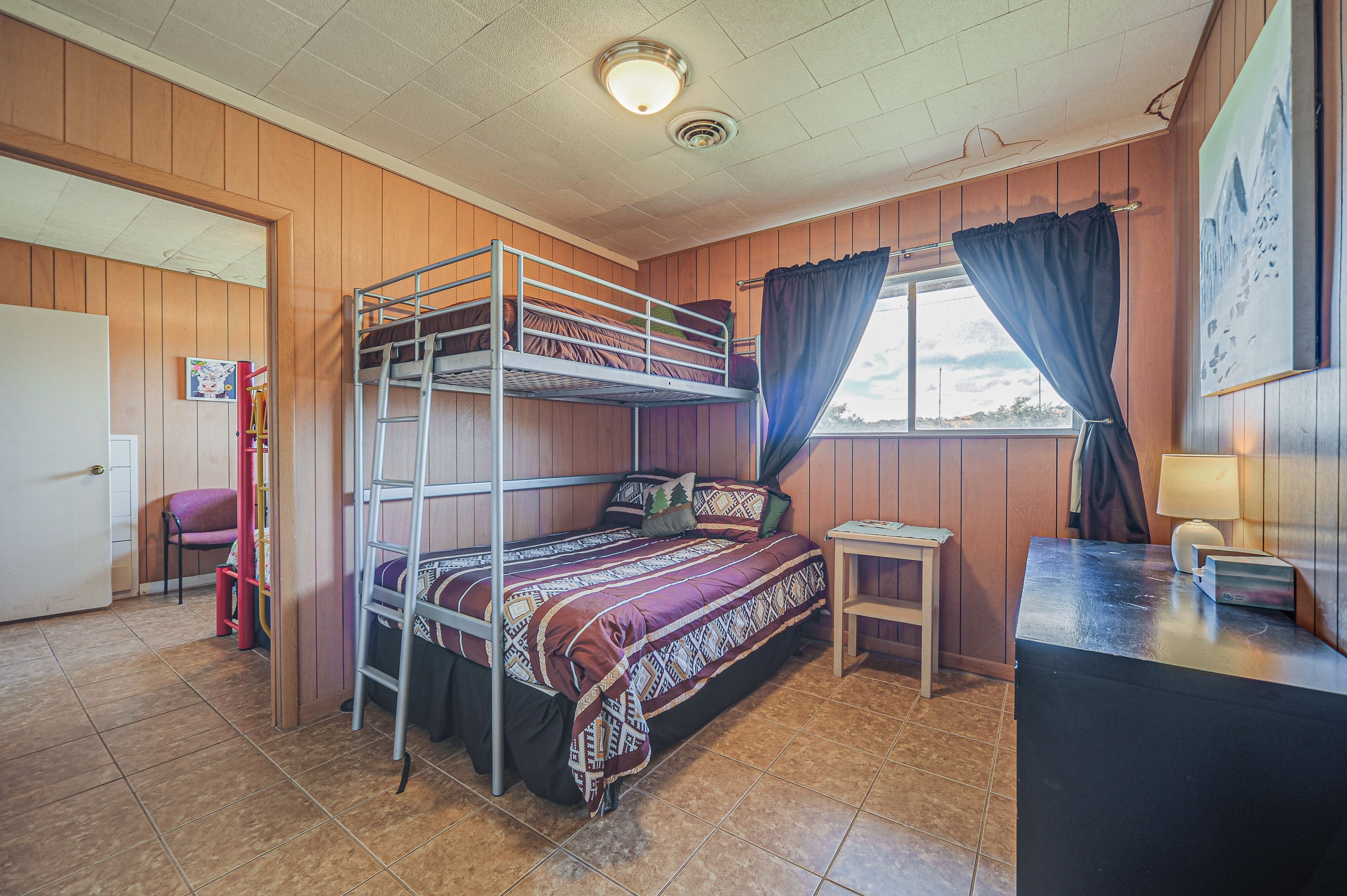 A bunk bed room with a desk and a window.