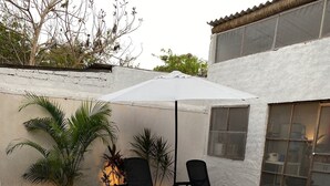 Piscina con piastrelle di mosaico blu, circondata da un muro bianco e da un patio con sedie e piante.