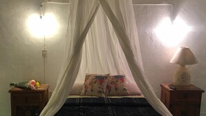 Un letto a baldacchino, due comodini, una lampada e una parete con un punto luce.
